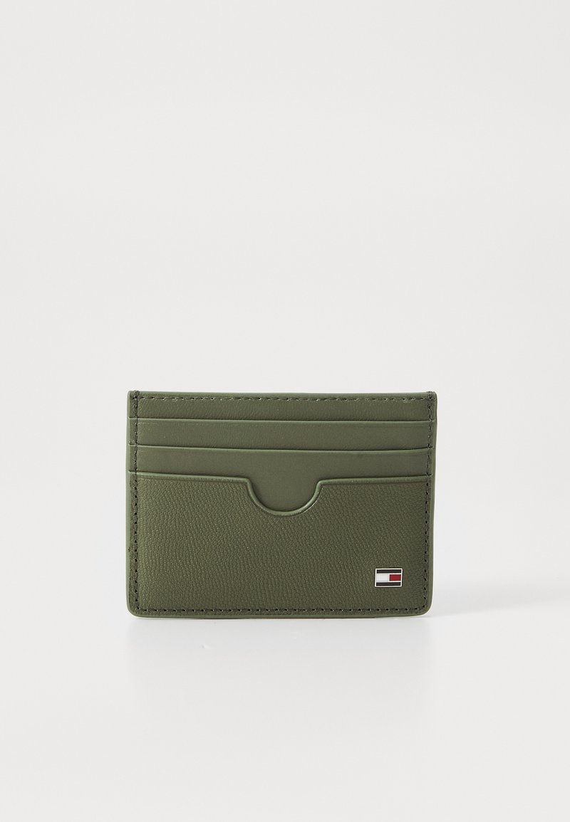 Green leather card holder with four card slots, textured exterior, and a small logo tag on the bottom right corner. Compact rectangular shape.