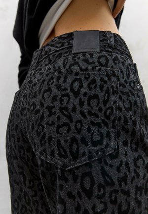 Zwarte spijkerbroek van denim met een gestructureerd luipaardpatroon, voorzien van een achterzak en een zwart leren label op de tailleband.