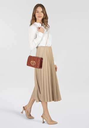 Rote gesteppten Leder-Umhängetasche mit goldenen Logodetails, Kettenriemen, präsentiert mit einer weißen Bluse und einem beigefarbenen plissierten Rock.