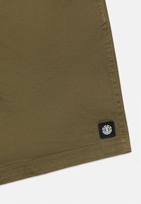 Tessuto verde oliva con una superficie liscia, con una toppa logo bianca e nera all'orlo e cuciture doppie per una maggiore durabilità.