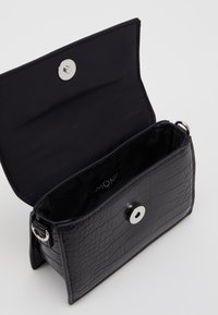 Borsa a tracolla nera con motivo a coccodrillo, chiusura magnetica con scatto, interno liscio e dettagli in metallo argentato.