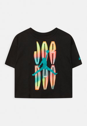 Top corto negro de manga corta con texto distorsionado y colorido "JORDAN" y logo azul de Jumpman de un jugador de baloncesto en pose de mate en el aire.