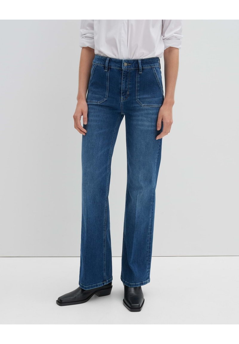 Jeans in denim azzurro chiaro con vita alta, taglio wide-leg e due tasche frontali. Abbinati a stivali alla caviglia neri con punta quadrata.