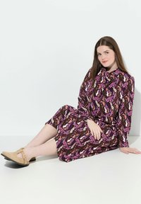Vestido de manga larga con un vibrante patrón abstracto multicolor que presenta tonos de rosa, marrón y crema. Tejido suave, corte a media pierna.