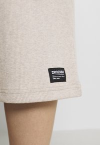 Béžové ribstoffé šortky s viditelným šitím, bočním lemem a černou etiketou s nápisem "DRDENIM DENIM & STREETWEAR OD ROKU 2004."