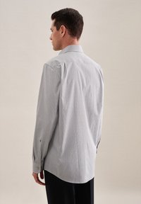 Camicia button-up blu chiaro con un motivo geometrico sottile, maniche lunghe e orlo arrotondato. Presenta bottoni dorati ai polsini.