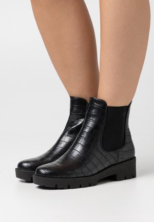 Botas de tobillo de piel sintética de cocodrilo negro con paneles elásticos laterales, suelas de goma negra maciza y punteras redondas. Detalle de superficie texturizada presente.