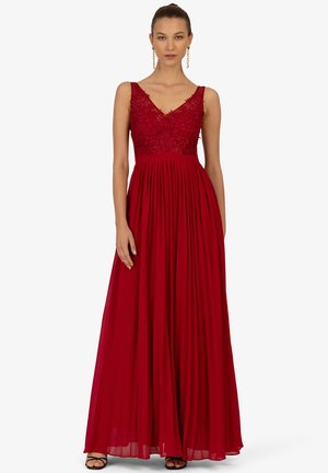 Rotes Kleid mit einem enganliegenden Spitze-Oberteil und plissiertem Rock. Es hat einen tiefen V-Ausschnitt und verstellbare Träger, ist bodenlang und hat eine glatte Textur.