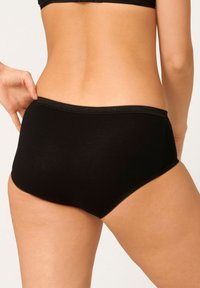 Mutande nere a vita alta realizzate in un materiale morbido ed elastico, con una texture liscia e un delicato bordo picot lungo l'elastico in vita e le aperture delle gambe.