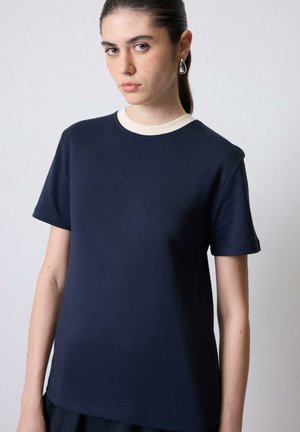 Mørkeblå t-shirt med en cremefarvet ribbet halsudskæring. Korte ærmer og en afslappet pasform, lavet af et glat, let stof.