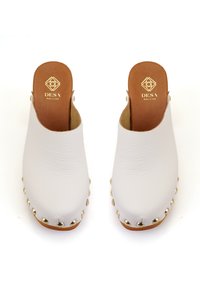 Sabots en cuir blanc avec une finition texturée, dos ouvert, bout arrondi et accents en studs dorés le long de la semelle extérieure. Logo de la marque sur la semelle intérieure.