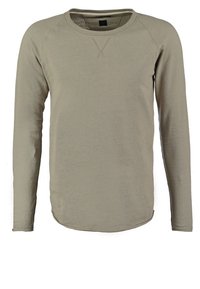 Lange mouwen, ronde hals shirt gemaakt van gestructureerde, lichtbruine stof. Heeft raglanmouwen en een afgeronde zoom. Eenvoudig, ingetogen ontwerp.