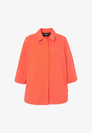 Veste corail-orange en tissu texturé, dotée d'un col, de manches 3/4 et de poches latérales. Accent en or notable sur le bas.