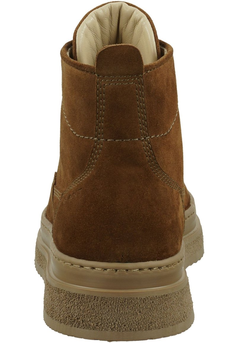 Bottes ankle en daim marron avec un col rembourré, semelle texturée beige et détails de couture visibles. Doublure intérieure en cuir lisse.