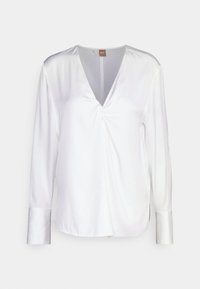 Bílá saténová blůza s dlouhým rukávem a hlubokým výstřihem do V, s nařaseným detailem uprostřed a knoflíkovými manžetami. Hladká textilie a uvolněný střih.