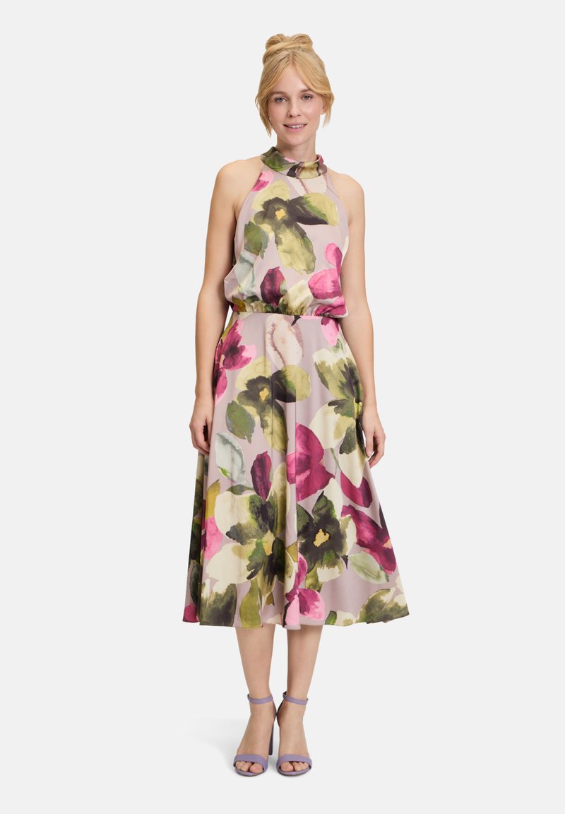 Robe midi sans manches à fleurs avec une taille froncée, présentant de grandes fleurs roses, vertes et jaunes sur un fond clair ; avec un col halter noué.