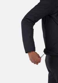 Schwarze gepolsterte Jacke mit langen Ärmeln, ausgestattet mit einem Kordelzug in der Taille und einer glatten, leichten Stoffstruktur.