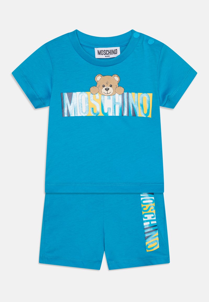 Türkises Baumwoll-Babyoutfit bestehend aus einem T-Shirt mit kurzen Ärmeln, das ein Bärenmotiv und den Schriftzug "MOSCHINO" zeigt, kombiniert mit passenden Shorts.