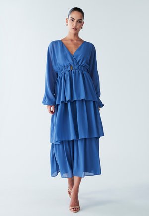 Robe bleue à plusieurs couches en tissu léger, dotée d'un décolleté en V, d'une taille élastique et de manches longues, avec une silhouette fluide et une texture douce.