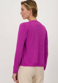 Fuchsia gebreide trui met lange mouwen en een ronde halslijn, voorzien van een subtiele glans. Ribgebreide zoom en manchetten, minimalistische details aan de achterkant.