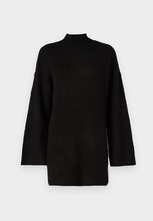 Crni oversized pleteni pulover s visokim ovratnikom i dugim rukavima, koji ima teksturiranu tkaninu za dodatni vizualni interes.