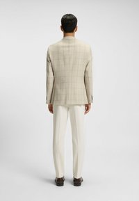 Beige rutigt blazer, skräddarsydd passform, slät tyg. Matcher med krämfärgade byxor och mörkbruna skor för en enhetlig look.