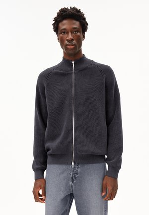 Dark grey zip-up sweater made of ribbed knit fabric. Features a high collar and raglan sleeves with a smooth texture.