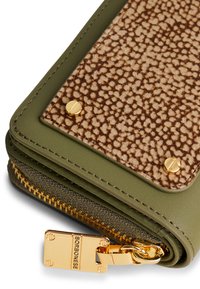 Gros plan sur le coin d'un portefeuille vert avec un panneau marron texturé, des rivets dorés et une tirette de fermeture éclair en or gravée "Borbonese".