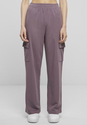 Lilla bomulls cargobukser med elastisk midje, sidelommer og løs passform, sammen med hvite joggesko.