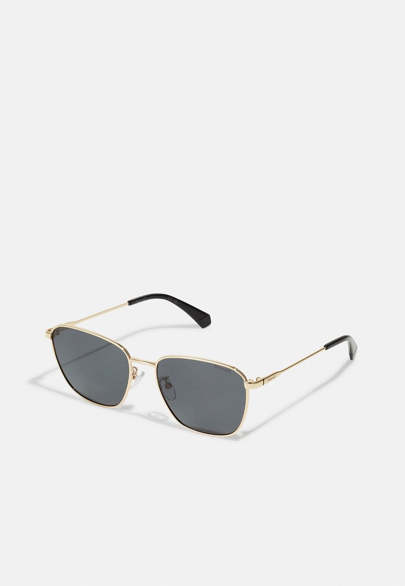 Ochelari de soare cu un cadru din metal auriu, lentile gri închise și vârfuri negre ale templelor. Formă rectangulară cu tampoane nazale transparente.
