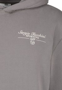 Grijze hoodie van zacht katoen met een trekkoord capuchon. Heeft het geborduurde logo "Sergio Tacchini Sportivo 1966" in het wit.