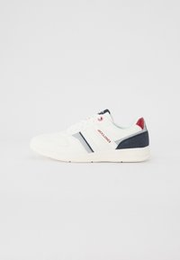 White athletic shoe with navy and red accents, textured upper, smooth sole, and subtle stripe design. Features branding on tongue and side.