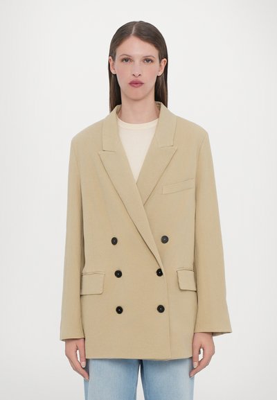 Beige, zweireihiger Blazer aus leichtem Material. Verfügt über schwarze Knöpfe, Reverskragen und zwei Fronttaschen. Glatte Textur.