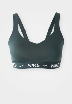 Donkergroene sportbeha met een V-halsontwerp, verstelbare straps en een brede zwarte band met witte "NIKE" branding. Soepele textuur.