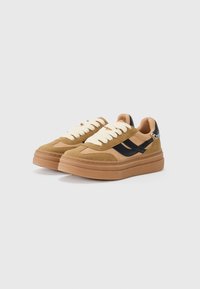 Brune sued og sandfarget lær sneakers med svarte detaljer, med tykke såler og kremfargede snører. Minimalistisk design med preget merkevare på siden.