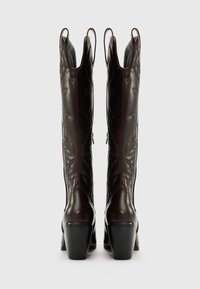 Bottes de cowboy en cuir marron, arrivant au genou, avec des motifs de feuilles en relief, un talon large et des languettes en haut pour un enfilage facile.