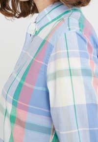 Camicia con bottoni caratterizzata da un motivo a quadri multicolore nei toni del blu, verde, rosa e bianco. Tessuto morbido e leggero con colletto aperto.
