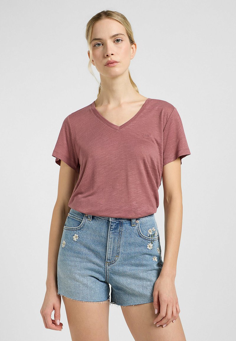 T-shirt V-neck color maroon realizzato in tessuto leggero, abbinato a pantaloni shorts in denim blu chiaro con ricamo floreale sul davanti.