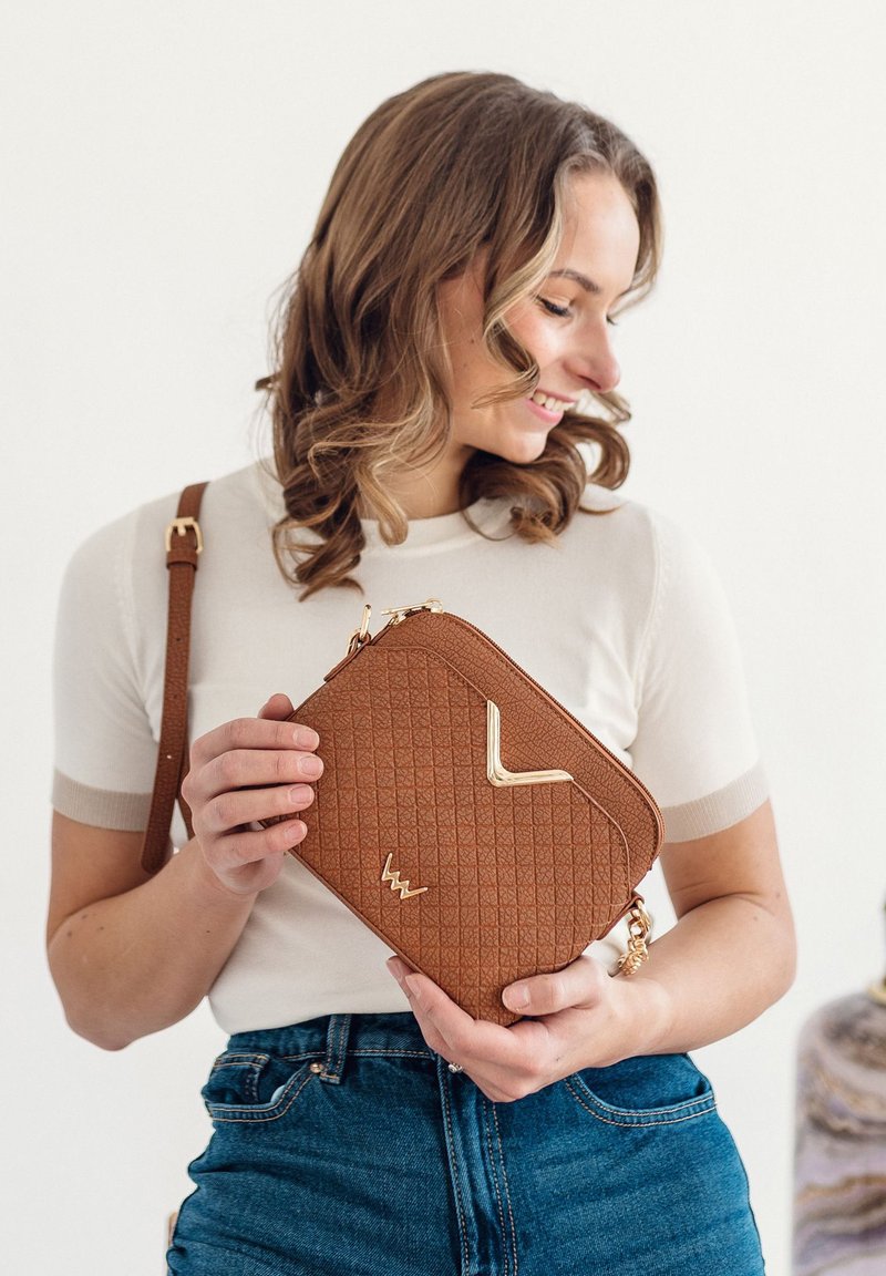 Brown leather crossbody bag with diamond quilted texture and gold accents. Features a zip closure and a detachable strap.