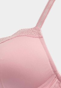 Rosa bh med slät tyg, spetskant längs kanten och justerbara band. Rundade kupor och sömlös design för komfort.