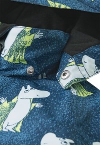 Atsparus vandeniui lietpaltis, pasižymintis mėlynu audiniu su Moomin personažų atvaizdais, spaudėmis ir minkštu apykaklės pamušalu, užtikrinančiu komfortą.
