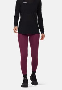 Vinröda leggings med en slät textur, förstärkta sömmar och hög midja, kombinerat med en långärmad svart topp och mörka skor.