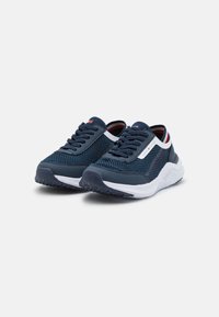 Scarpe atletiche blu navy con tomaia in mesh, dettagli bianchi, suole testurizzate e design con lacci; presentano una fodera a righe rosse e bianche.