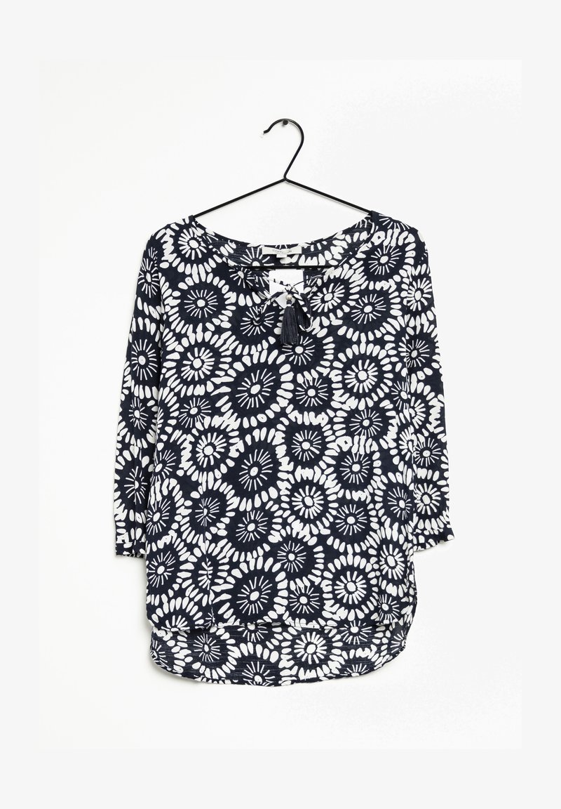 Blusa blu navy con motivo floreale bianco, scollatura rotonda e maniche 3/4; presenta un dettaglio con fiocco e un orlo curvo.