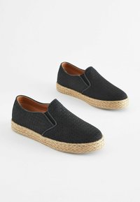 Schwarze gewebte Slipschuhe mit elastischem Einsatz, natürlicher Jutenzwischensohle und glatter brauner Innenauskleidung. Schlichtes Design, runde Zehenpartie.