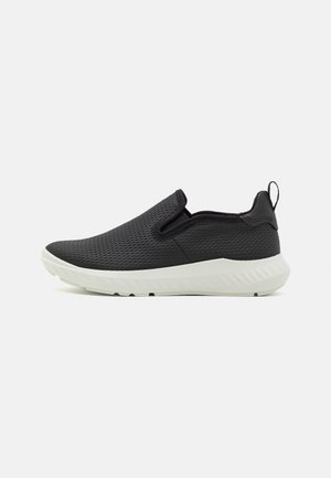 Czarny wsuwany sneaker z oddychającą cholewką z siateczki, białą miękką podeszwą i pętelką na pięcie, widoczny z boku na jasnym tle.