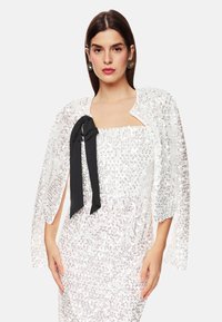 Weißer Pailletten-Jacket mit schwarzem Schleifendetail. Verfügt über offene Ärmel und hat eine strukturierte Optik, die das formelle Design unterstreicht.