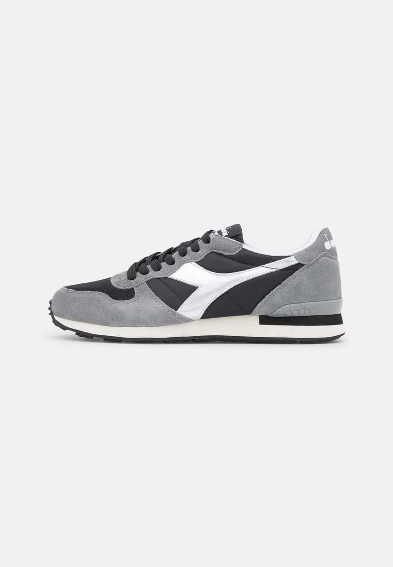 Baskets grises et noires avec logo blanc, lacets noirs et semelle blanche et noire, vues de côté sur fond blanc.