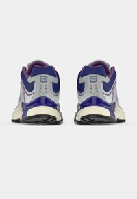 Men's running shoes with a grey upper, purple accents, and a patterned sole. Features padded collar and lacing system for secure fit.