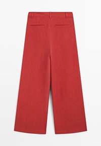 Wijde cropped broek in verbrande oranje kleur met riemlussen en twee achterzakken op een witte achtergrond.